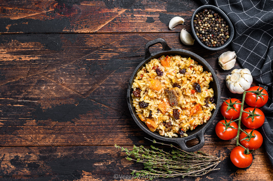Pilaf in a pan. Central Asian cuisine Plov.  Dark wooden background. Top view. Copy space.