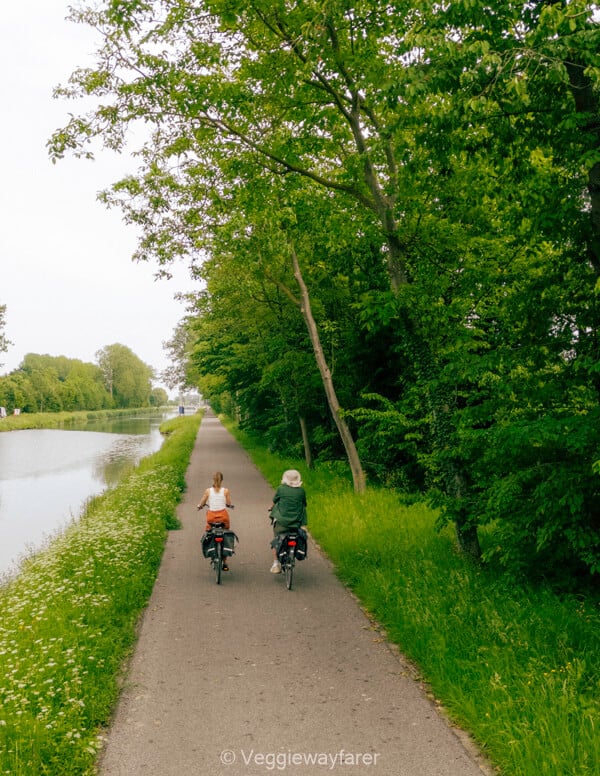 Two cyclists riding the towpath beside the canal on the edge of Leuven