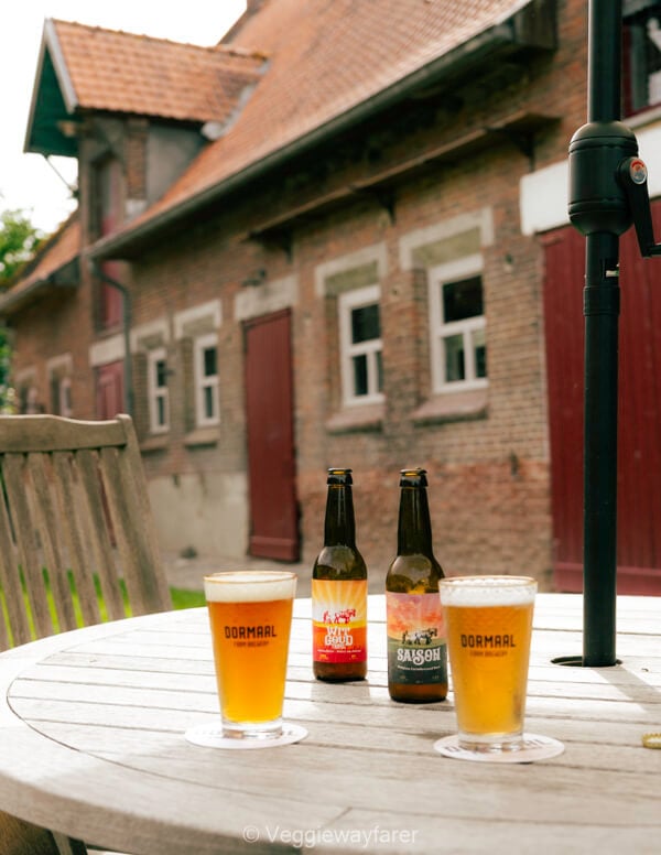 Bottles of Wit Goud and Saison with Dormaal glasses on an outdoor table at the Hof ten Dormaal farm brewery