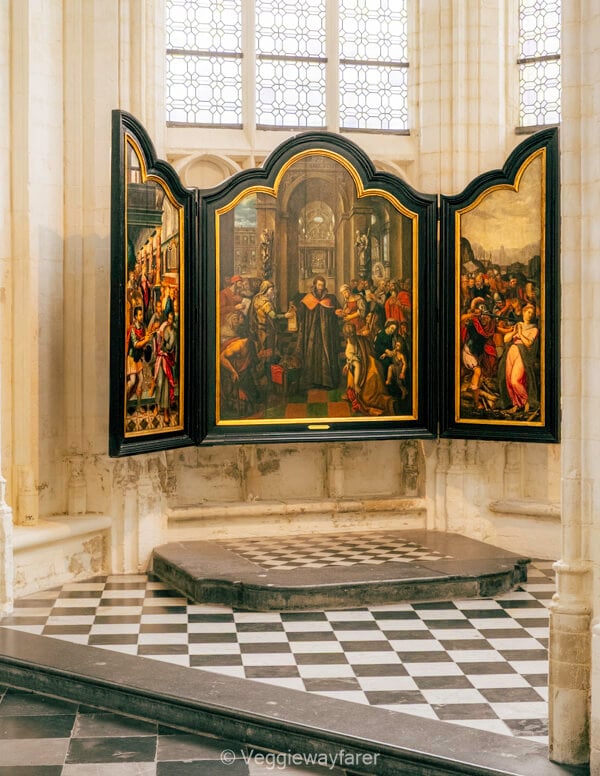 Painted triptych in a side chapel of Sint-Pieterskerk in Leuven, above a black and white tiled floor