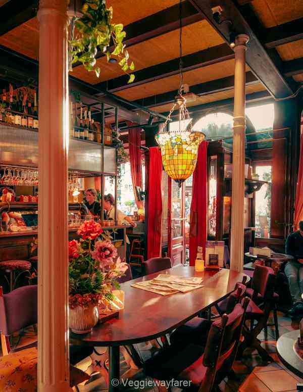 cozy bar with an art nouveau lamp, a big wooden table with newspapers on it in Utrecht Netherlands
