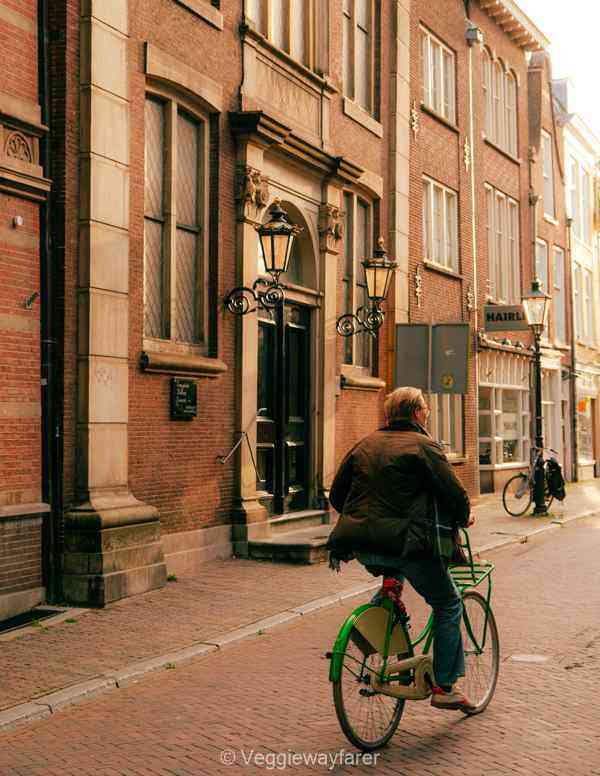 man cycling past an old building in Utrecht Netherlands